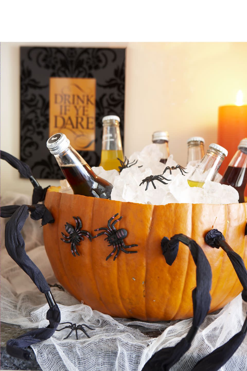 <p>Cut a large pumpkin in half and scoop the insides out of the bottom portion. Fill with ice and decorate it with faux spiders, and you've got the spookiest drink display on the block.</p>