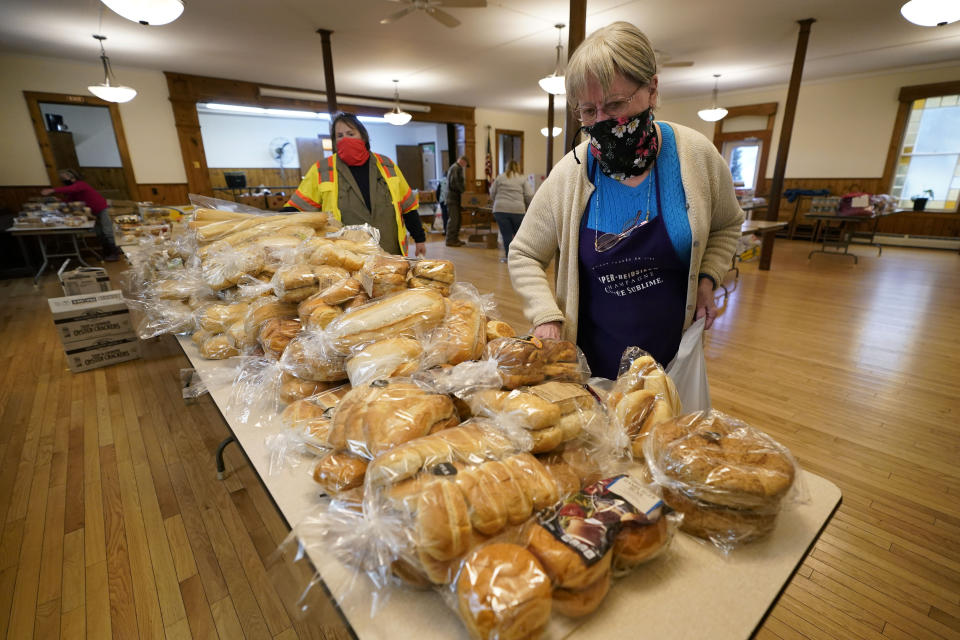 Faylene McKeen selects a package of bread to be given away at a food pantry she oversees at the First Universalist Church, Wednesday, Nov. 25, 2020, in Norway, Maine. (AP Photo/Robert F. Bukaty)