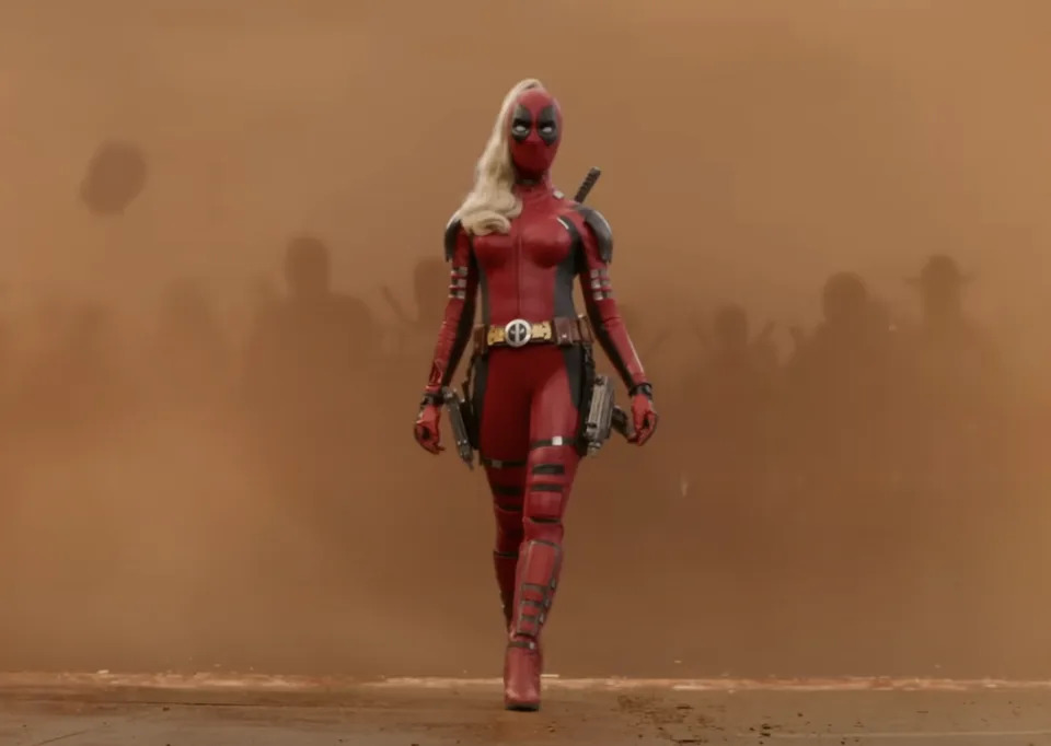 Lady Deadpool, in a red and black suit, strides confidently amid a sandstorm