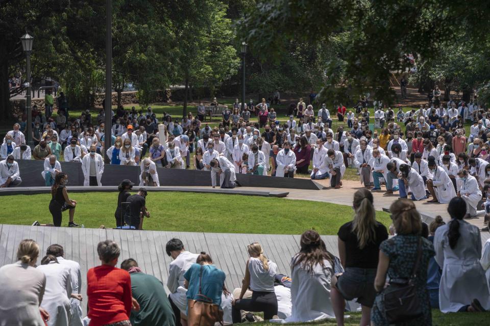 People gather to show support for the “White Coats for Black Lives” movement, which has worked to raise awareness of police brutality, inequality, and racism, at the University of Virginia's Memorial to Enslaved Laborers.