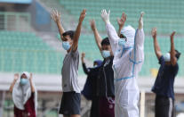 A health worker, right, wearing protective suit performs exercise with COVID-19 patients at at Patriot Candrabhaga stadium which is recently turned into isolation center for people showing symptoms of the disease amid the coronavirus outbreak in Bekasi on the outskirts of Jakarta, Indonesia, Monday, Sept. 28, 2020.(AP Photo/Achmad Ibrahim)