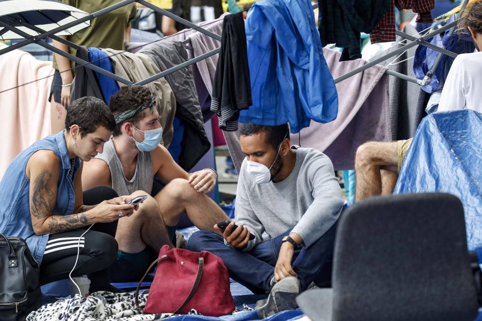 Protesters gather at an encampment outside City Hall, Tuesday, June 30, 2020, in New York. City Council members were due to debate and vote Tuesday night on a plan to shift $1 billion from policing to education and social services, with time running short ahead of the fiscal year that begins Wednesday. (AP Photo/John Minchillo)