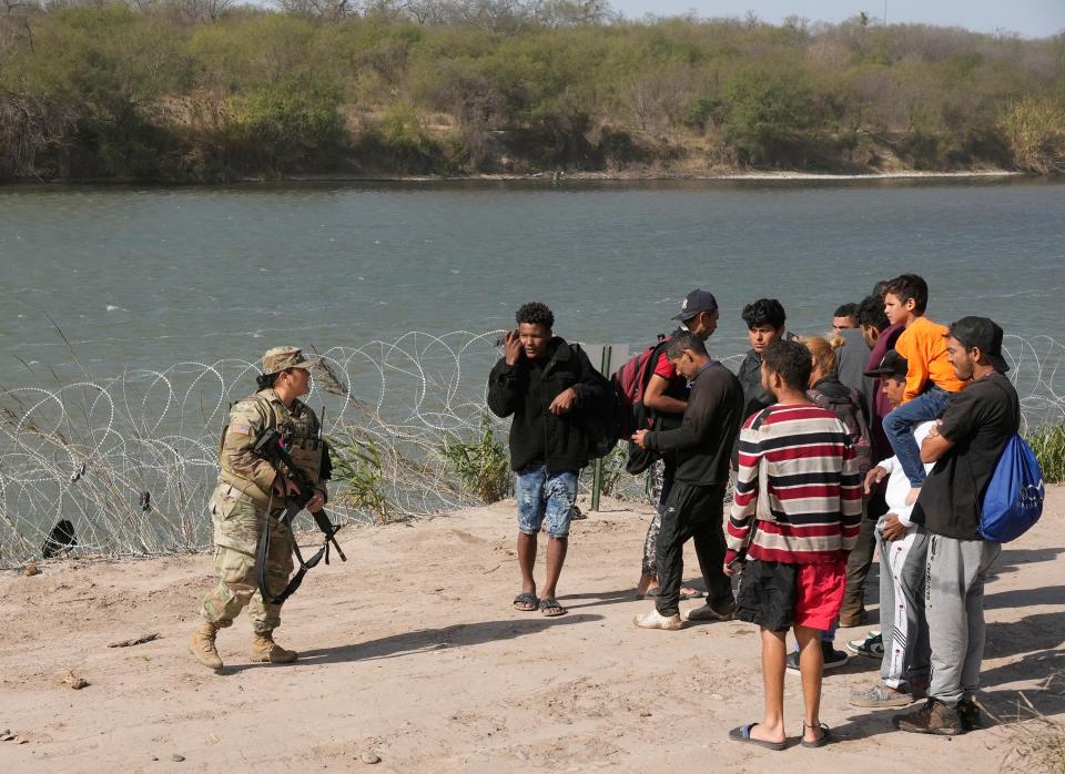 A Texas National Guard soldier talks to a group of Venezuelan migrants on the banks of the Rio Grande before they surrendered Jan. 8 to the Border Patrol. Texas and the federal government are at odds over jurisdiction along the border.