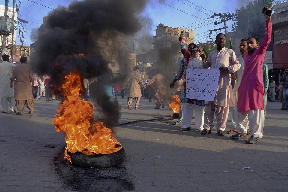 Supporters of former Prime Minister Imran Khan's party chant slogans next to burning tires while they block a road as a protest against the Election Commission's decision to disqualify their leader Khan, Friday, Oct. 21, 2022, in Hyderabad, Pakistan. Officials say Pakistan’s elections commission has disqualified former Prime Minister Imran Khan from holding public office for five years, after finding he had unlawfully sold state gifts and concealed assets as premier. (AP Photo/Pervez Masih)