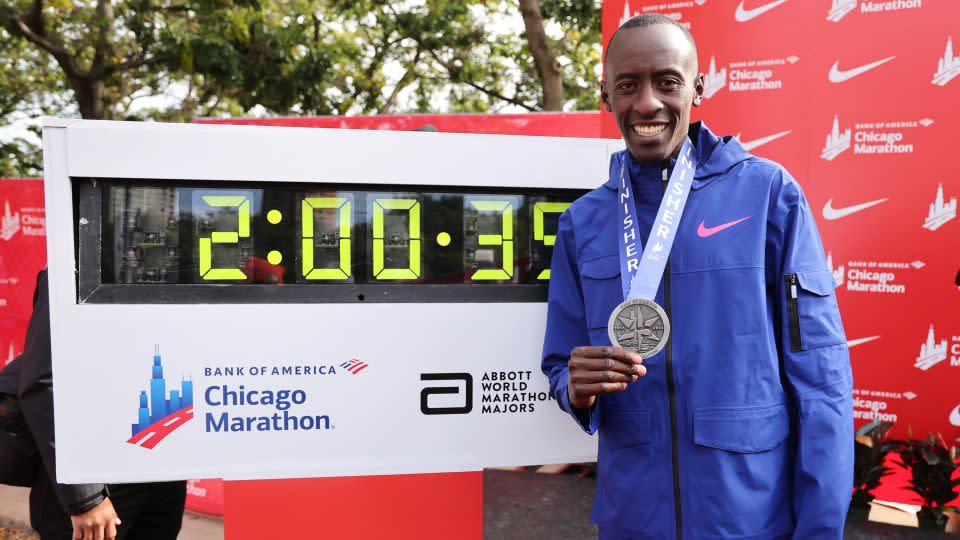 Kiptum poses with his medal and the clock after setting a world record men's marathon time of 2:00:35. - Michael Reaves/Getty Images