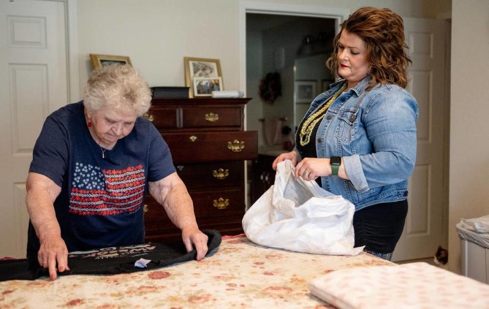 End-of-life doula Ashley Boydston, right, helps Jeannine Binder clean out a dresser full of her late husband’s clothes at her home in Shawnee. Binder’s family hired Boydston to help them through the last stages of John Binder’s life. He died in April.