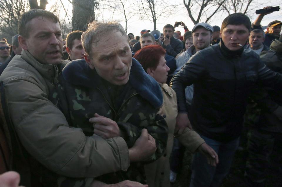 Pro-Russian activists attack Ukraine's security services anti-terrorist unit chief, Gen. Vasyl Krutov, center, after he spoke outside Kramatorsk airport, eastern Ukraine, Tuesday, April 15, 2014. In the first Ukrainian military action against a pro-Russian uprising in the east, government forces clashed Tuesday with about 30 armed gunmen at a small airport in Kramatorsk. (AP Photo/Sergei Grits)