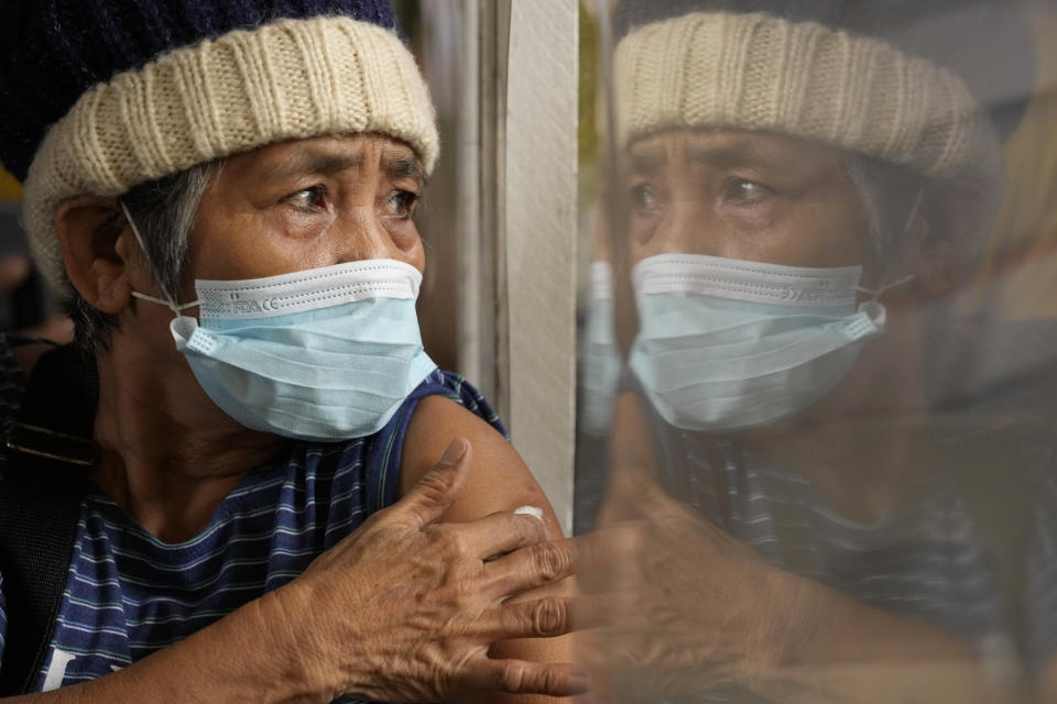 A woman holds onto a cotton pad after being inoculated with AstraZeneca's COVID-19 vaccine during the first day of a nationwide three-day vaccination drive at a school in Quezon city, Philippines on Monday, Nov. 29, 2021. There has been no reported infection so far caused by the new variant in the Philippines, a Southeast Asian pandemic hotspot where COVID-19 cases have considerably dropped to below 1,000 each day in recent days, but the emergence of the Omicron variant has set off a new alarm. (AP Photo/Aaron Favila)