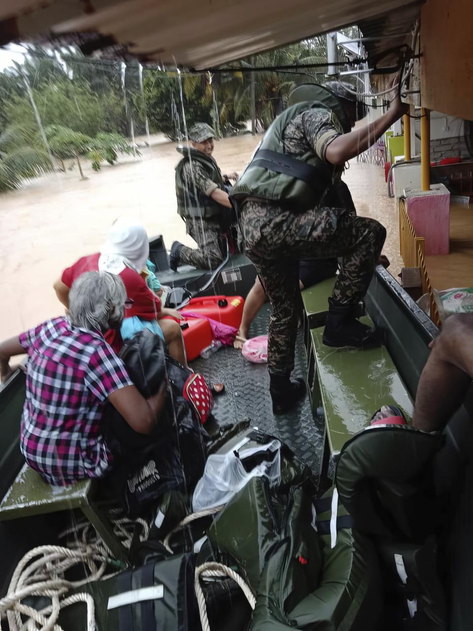 In this photo released by National Disaster Management Agency, the army evacuate residents on Chaah town in Segamat, in southern Johor state, Malaysia, Wednesday, March 1, 2023. Rescuers in boats plucked flood victims trapped on rooftops and hauled others to safety as incessant rain submerged homes and villages in parts of Malaysia, leading to over 26,000 people evacuated as of Thursday. (National Disaster Management Agency via AP)
