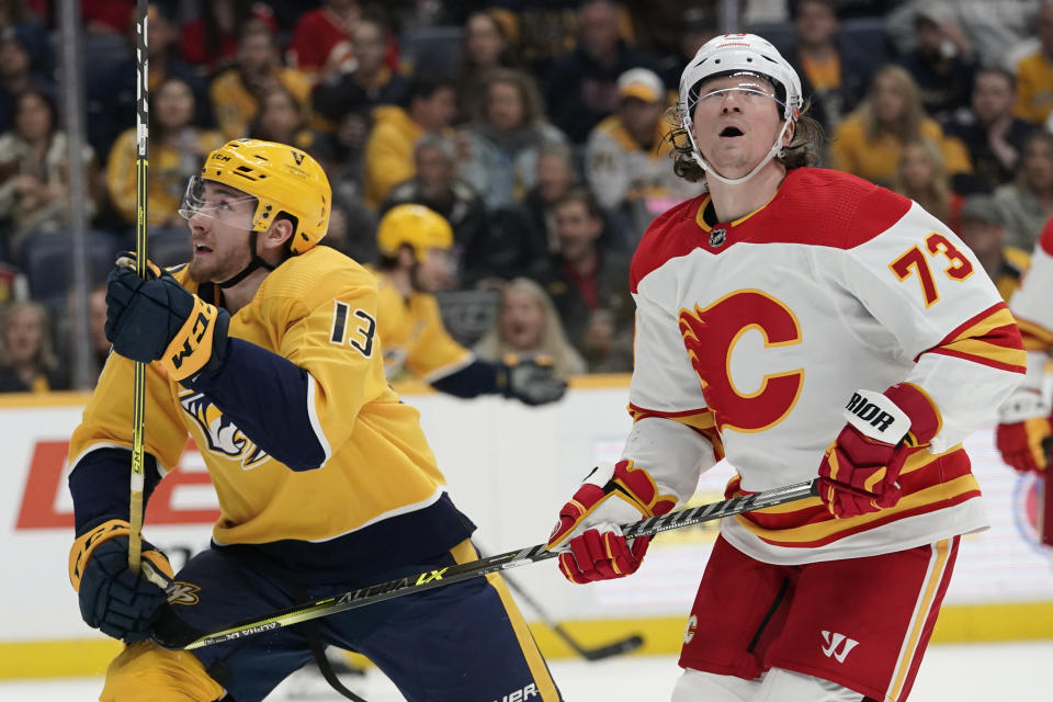 Nashville Predators' Yakov Trenin (13) and Calgary Flames' Tyler Toffoli (73) look for the airborne puck in the second period of an NHL hockey game Tuesday, April 19, 2022, in Nashville, Tenn. (AP Photo/Mark Humphrey)