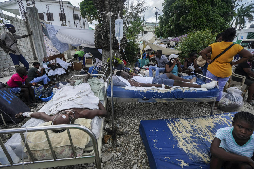 FILE - Injured people lie in beds outside the Immaculee Conception Hospital in Les Cayes, Haiti, Aug. 16, 2021, two days after an earthquake struck the southwestern part of the country. The magnitude 7.2 earthquake in mid-August destroyed tens of thousands of homes and killed more than 2,200 people. (AP Photo/Fernando Llano, File)