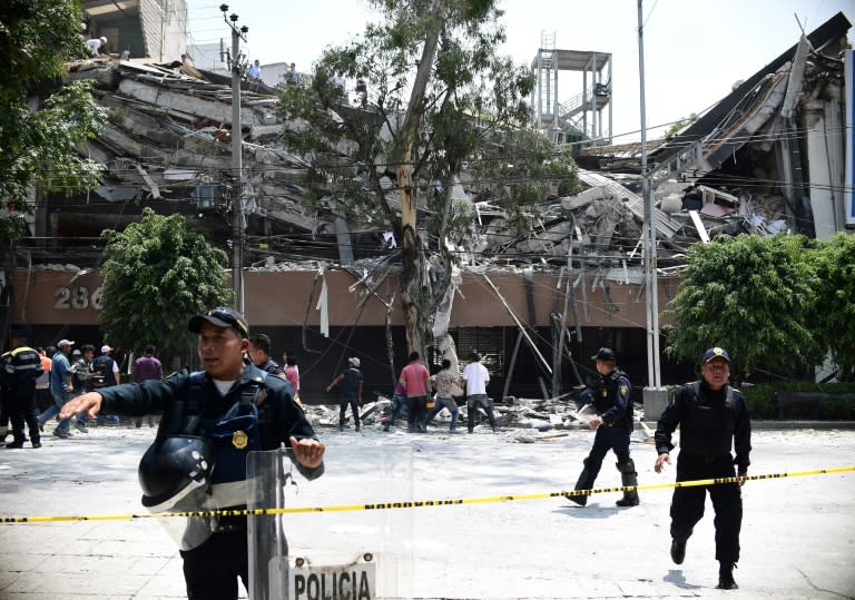 Police officers cordon off an area after a building collapses during a quake in Mexico City