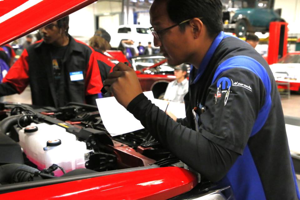 Carl Cuthair Jr. uses a flashlight to get a better look at the engine of a pickup truck during the Skills USA regional competition on Friday, Nov. 17 at San Juan College.