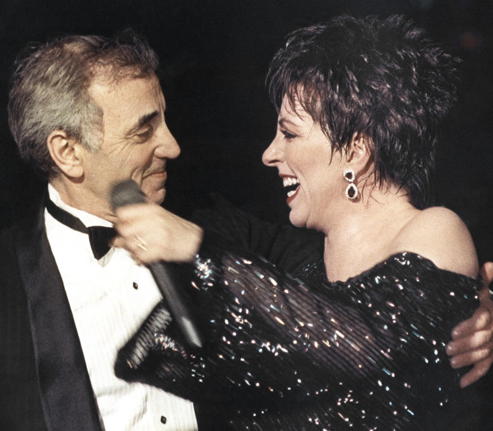 FILE - In this Nov.8, 1987 file photo, American singer Liza Minnelli welcomes French singer Charles Aznavour onto the stage at the end of her show at the Lido cabaret in Paris. Charles Aznavour, the French crooner and actor whose performing career spanned eight decades, has died. He was 94. (AP Photo/Laurent Rebours, File)