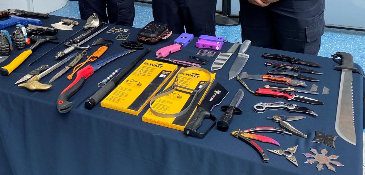 Transportation Security Administration officials display some of the knives, swords, electronic stun devices, guns, replicas and other prohibited items confiscated in the first half of 2022 from passengers checking in at Jacksonville International Airport.