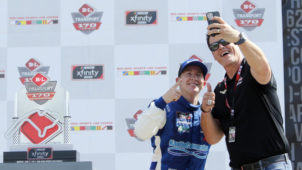 A.J. Allmendinger, left, takes a photo with car owner Matt Kaulig as they celebrate in Victory Lane after winning the B&L Transport 170 NASCAR Xfinity Series auto race at Mid-Ohio Sports Car Course on Saturday, June 5, 2021, in Lexington, Ohio. (AP Photo/Tom E. Puskar)