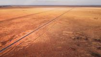 <p>Wide-open desert planes flank a lone highway.</p>