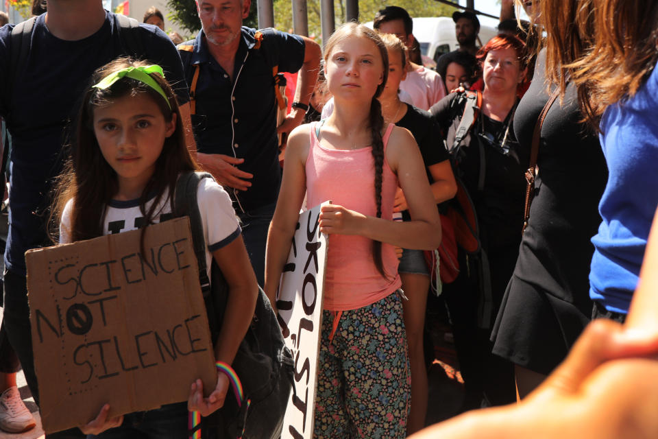 Swedish climate activist Greta Thunberg holding a sign in a crowd of people in New York City.