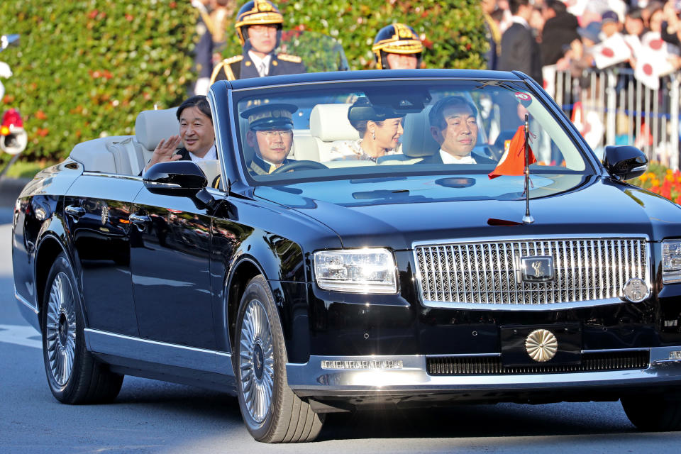 Japanese Emperor Naruhito, left, and Empress Masako, right, wave to spectators during a royal motorcade in Tokyo, Sunday, Nov. 10, 2019. (AP Photo/Koji Sasahara)