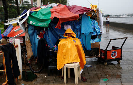A vendor takes shelter next to his closed shop in Manila as Typhoon Sarika slammed central and northern Philippines, October 16, 2016. REUTERS/Erik De Castro