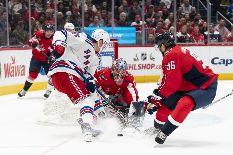 Washington Capitals goaltender Charlie Lindgren, center, blocks a shot by New York Rangers left wing Jimmy Vesey (26) while Washington Capitals right wing Nicolas Aube-Kubel (96) defends during the second period of an NHL hockey game, Saturday, Dec. 9, 2023, in Washington. (AP Photo/Stephanie Scarbrough)