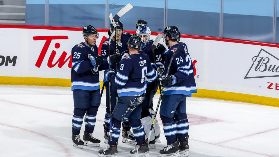 WINNIPEG, MB - FEBRUARY 2: Goaltender Laurent Brossoit #30 of the Winnipeg Jets is congratulated by teammates Paul Stastny #25, Mark Scheifele #55, Andrew Copp #9 and Derek Forbort #24 following a 3-2 victory over the Calgary Flames at the Bell MTS Place on February 2, 2021 in Winnipeg, Manitoba, Canada. (Photo by Jonathan Kozub/NHLI via Getty Images)