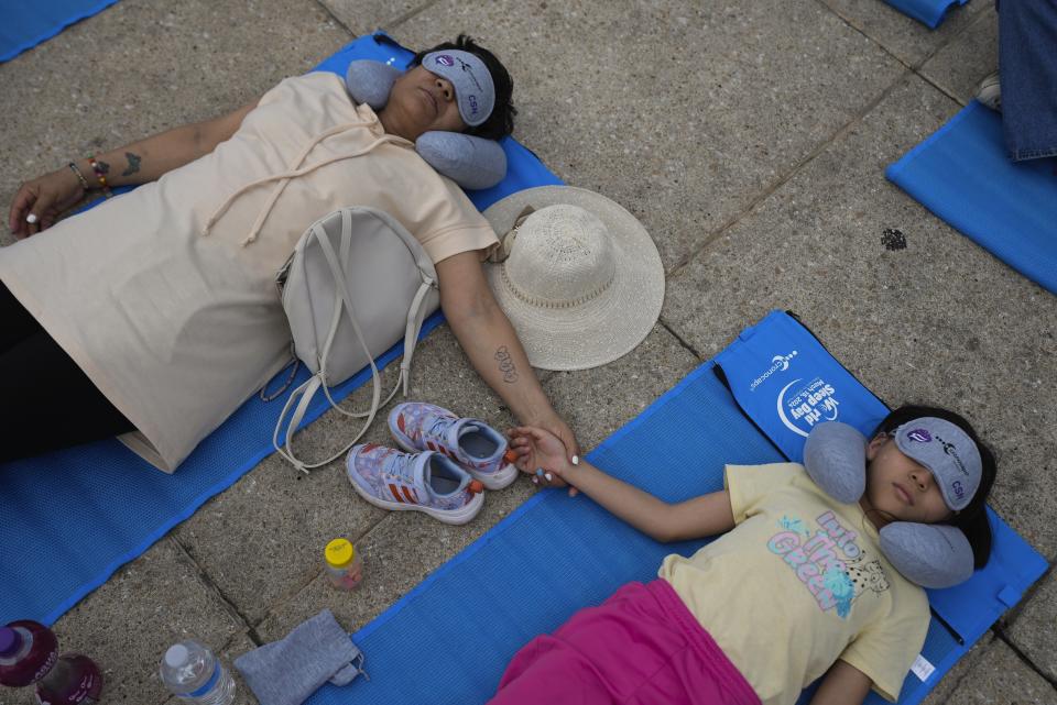 Equipped with mats, sleeping masks and travel pillows, a child and a woman take a nap at the base of the iconic Monument to the Revolution, during an event dubbed the “mass siesta,” commemorating World Sleep Day, in Mexico City, Friday, March 15, 2024. (AP Photo/Fernando Llano)