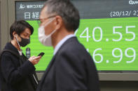 People walk by an electronic stock board of a securities firm in Tokyo, Wednesday, Dec. 2, 2020. Asian markets are mixed after the U.S. benchmark S&P 500 set another record. (AP Photo/Koji Sasahara)