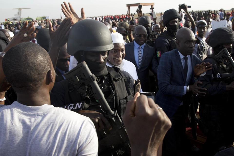 Gambian President Adama Barrow, centre, greets crowds after arriving at Banjul airport in Gambia, Thursday Jan. 26, 2017, after flying in from Dakar, Senegal. Gambia's new president has finally arrived in the country, a week after taking the oath of office abroad amid a whirlwind political crisis. Here's a look at the tumble of events that led to Adama Barrow's return — and the exile of the country's longtime leader. (AP Photo/Jerome Delay)