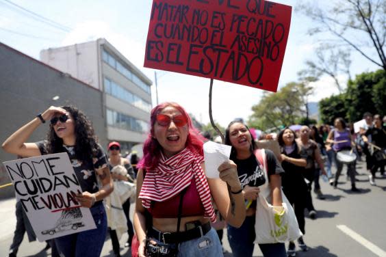 Women hold banners saying 'They don't look after me, they rape me' and 'Killing is not a sin when the murderer is the State' at the protest (EPA)