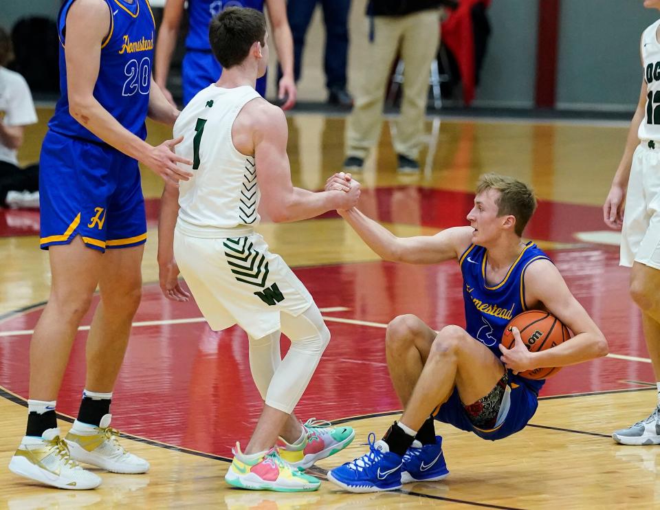 Westfield Shamrocks Braden Smith (1) helps Homestead Spartans Fletcher Loyer (2) after falling Saturday, Dec. 11, 2021, at Southport Fieldhouse, Indianapolis. Homestead Spartans defeated the Westfield Shamrocks, 55-58. 