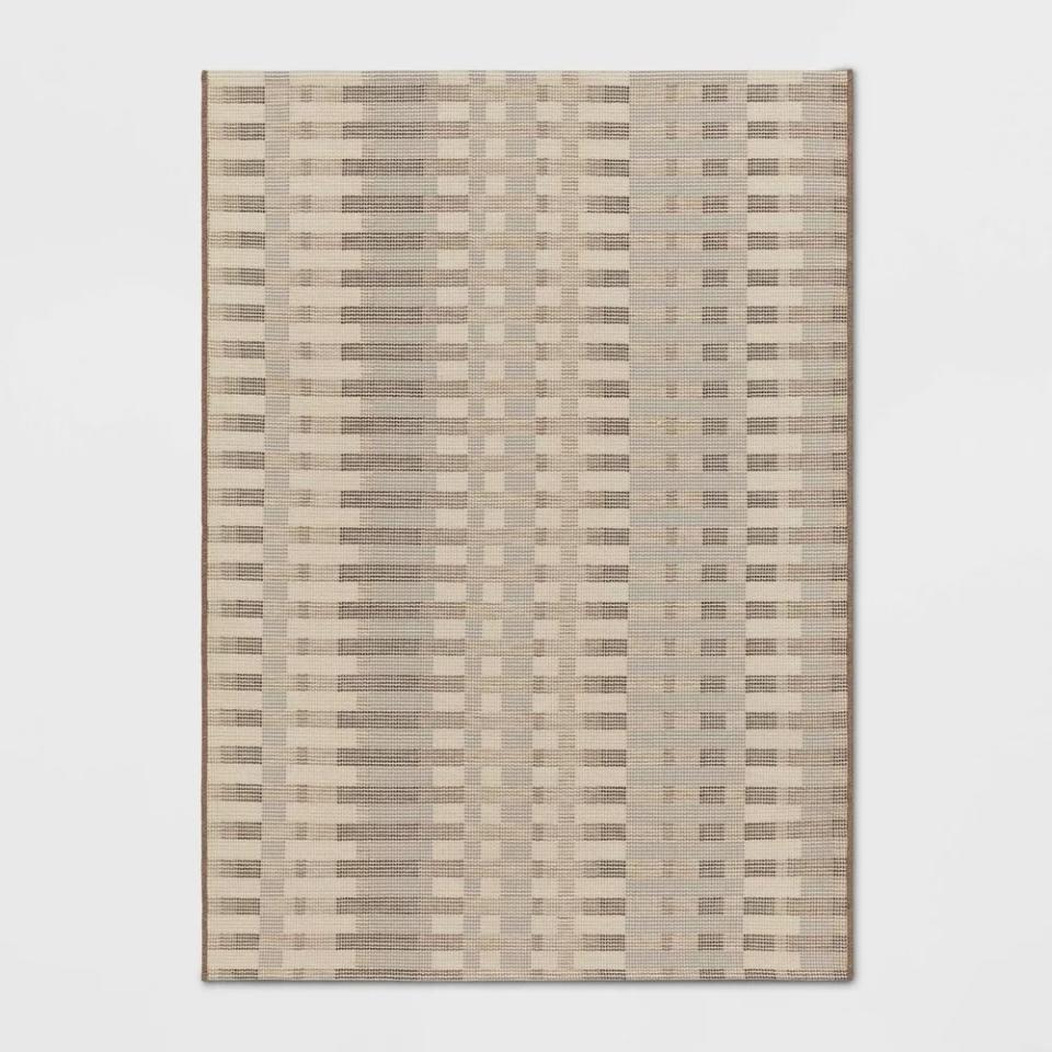 Rectangular rug with a neutral-toned, geometric pattern displayed for shopping