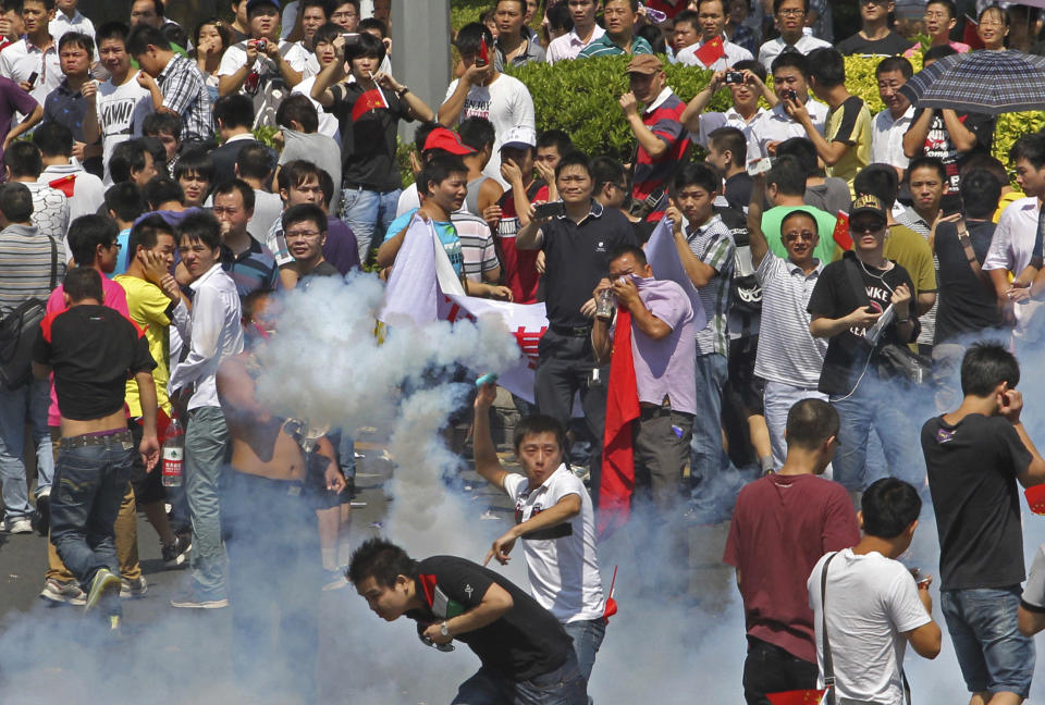 A Chinese demonstrator throws a teargas canister back to riot policemen during a protest against Japan in Shenzhen, China Sunday, Sept. 16, 2012. Protesters in China have begun another day of demonstrations against Japan, after protests over disputed islands spread across numerous cities and at times turned violent. (AP Photo/Apple Daily) HONG KONG OUT, TAIWAN OUT, NO SALES
