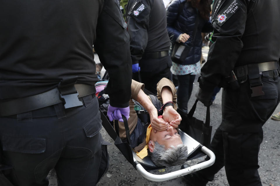 A climate change protester is carried off by police after being extracted from underneath a lorry outside the Home Office in London, Tuesday, Oct. 8, 2019. Police are reporting they have arrested more than 300 people at the start of two weeks of protests as the Extinction Rebellion group attempts to draw attention to global warming.(AP Photo/Alastair Grant)