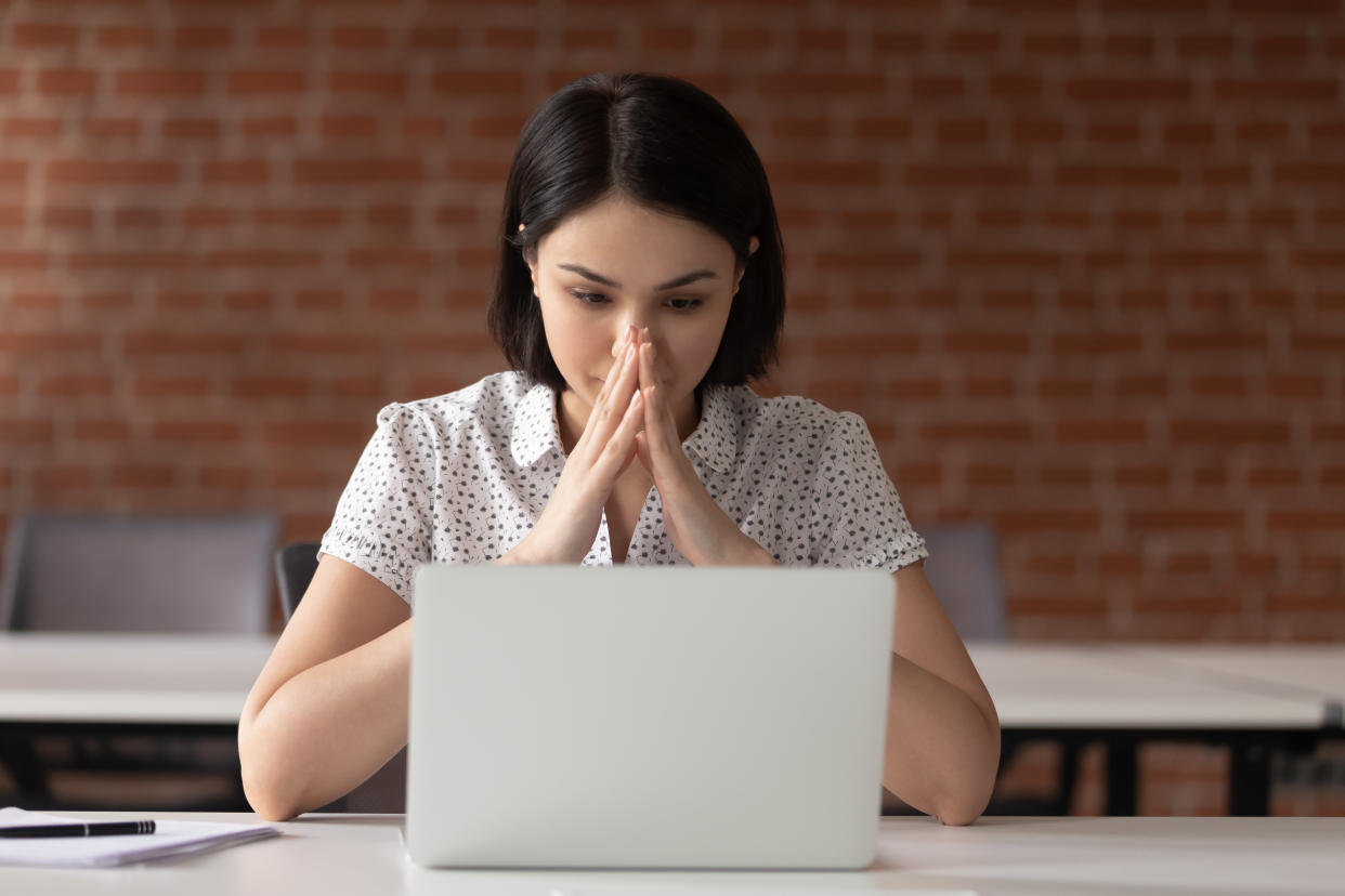 Pensive young female worker sit at office desk look at laptop screen thinking making decision, thoughtful woman employee pondering over problem solution, stare at computer monitor wait inspiration