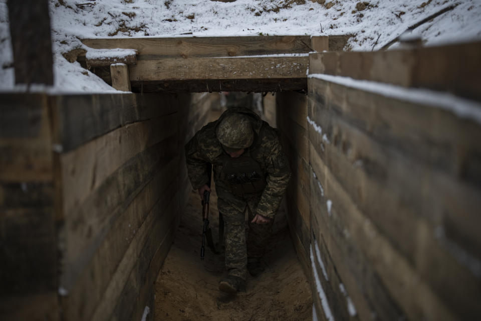 A Ukrainian serviceman walks through a trench at a position close to the border with Belarus, Ukraine, Wednesday, Feb. 1, 2023. Reconnaissance drones fly several times a day from Ukrainian positions across the border into Belarus, a close Russian ally, scouring for signs of trouble on the other side. Ukrainian units are monitoring the 1,000-kilometer (650-mile) frontier of marsh and woodland for a possible surprise offensive from the north, a repeat of the unsuccessful Russian thrust towards Kyiv at the start of the war nearly a year ago. (AP Photo/Daniel Cole)