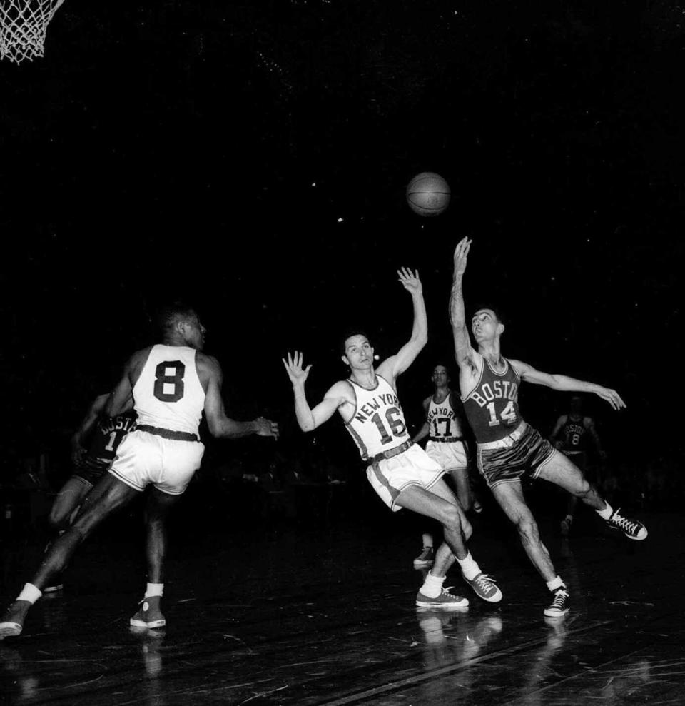 Al McGuire (16) of the <a class="link " href="https://sports.yahoo.com/nba/teams/new-york/" data-i13n="sec:content-canvas;subsec:anchor_text;elm:context_link" data-ylk="slk:New York Knickerbockers;sec:content-canvas;subsec:anchor_text;elm:context_link;itc:0">New York Knickerbockers</a> tries to balance himself after being bumped by Bob Cousy (14), Boston Celtics left guard, in the first quarter of pro basketball playoffs in Madison Square Garden on March 16, 1954. In the center background is Knicks’ Fred Schaus (17). AP Photo/Matty Zimmerman