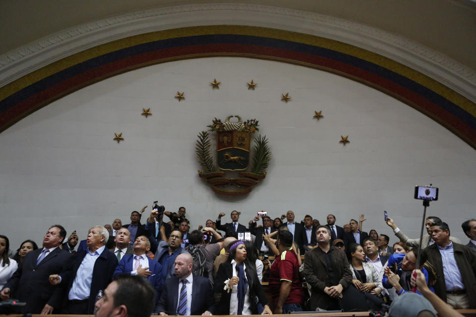 Opposition leader Juan Guaido, top center, and other opposition lawmakers, sing the national anthem after being temporarily blocked form entering the Legislative Palace, as they stand in the main podium area before the start of a session at the National Assembly in Caracas, Venezuela, Tuesday, Jan. 7, 2020. Venezuela’s opposition is facing its biggest test yet after government-backed lawmakers announced they were taking control of what Guaidó supporters have described as the nation’s last democratic institution. (AP Photo/Andrea Hernandez Briceño)