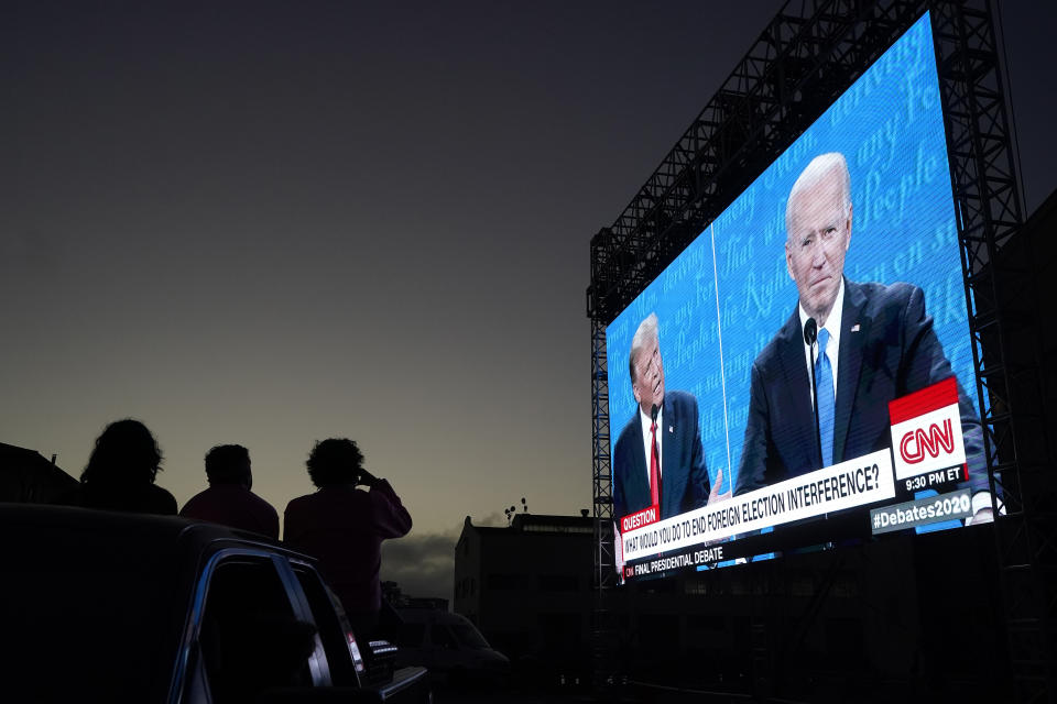 FILE - People watch from their vehicle as President Donald Trump, on left of video screen, and Democratic presidential candidate former Vice President Joe Biden speak during a Presidential Debate Watch Party at Fort Mason Center in San Francisco, Thursday, Oct. 22, 2020. Unflattering portraits of both Biden and Trump emerge clearly in a new poll by The Associated Press-NORC Center for Public Affairs Research, which asked an open-ended question about what comes to mind when people think of them. (AP Photo/Jeff Chiu, File)