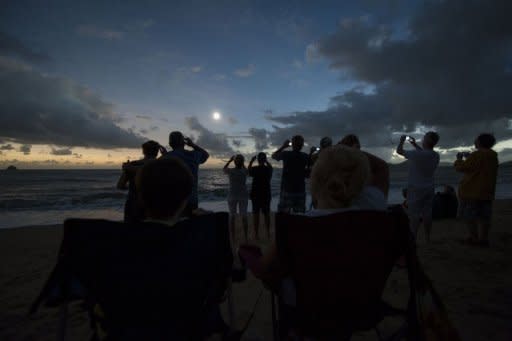 People view the solar eclipse from the beach at Palm Cove in Australia's tropical north Queensland on November 14, 2012. Tens of thousands of sky-gazers flocked to watch the moon block out the sun in one of nature's greatest phenomena -- a total solar eclipse