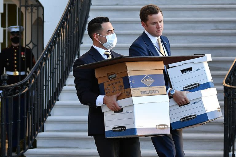 Una foto del 20 de enero de 2021 muestra a los ayudantes que llevan cajas a Marine One antes de que el presidente de los Estados Unidos, Donald Trump, y su esposa Melania Trump partieran de la Casa Blanca el último día de Trump en el cargo, en Washington, DC.