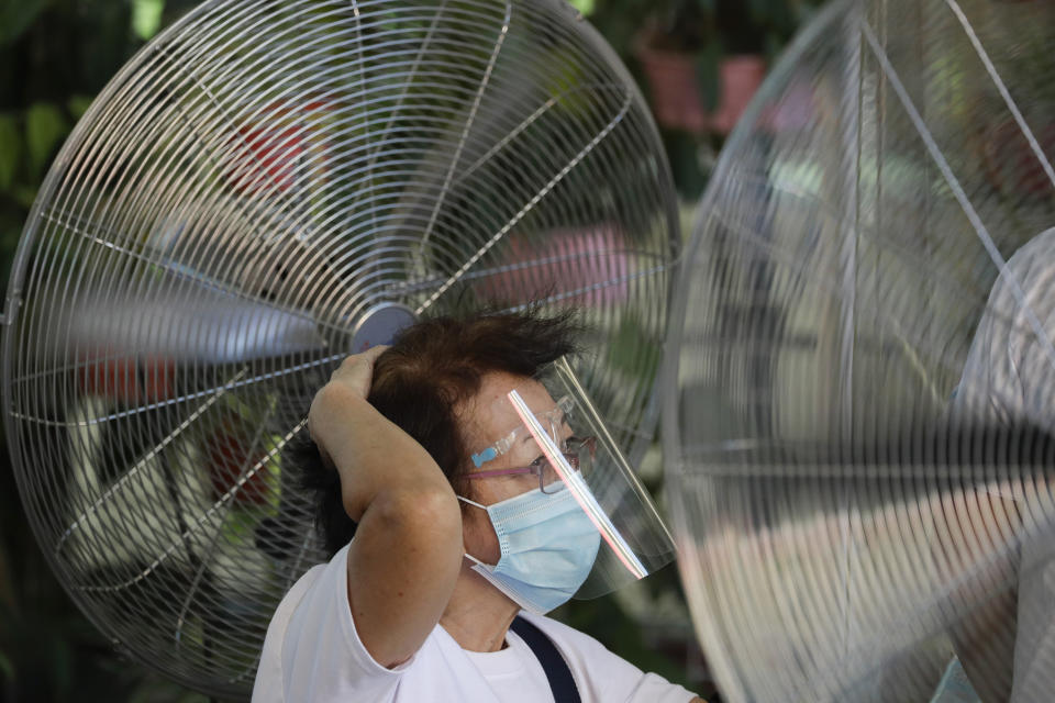 Standing in front of fans, a woman holds her hair as she waits to be inoculated with China's Sinovac COVID-19 vaccine in Quezon city, Philippines on Friday, May 14, 2021. The Philippine president has eased a coronavirus lockdown in the bustling capital and adjacent provinces to fight economic recession and hunger but still barred public gatherings this month, when many Roman Catholic summer religious festivals are held. (AP Photo/Aaron Favila)