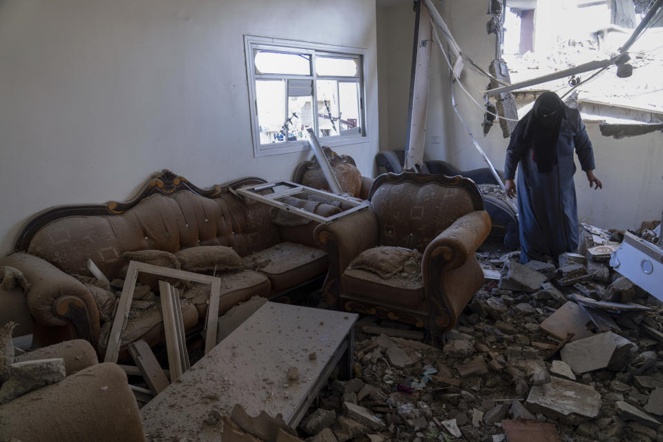 A Palestinian woman inspects a damaged house following Israeli airstrikes on the town of Khan Younis, Gaza, Sunday, Dec. 3, 2023. (AP Photo/Fatima Shbair)