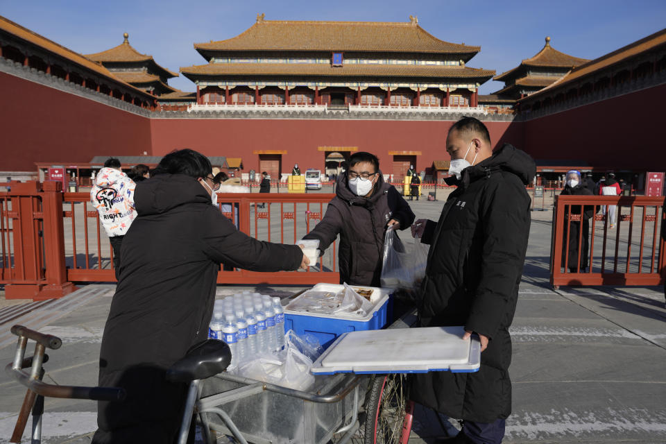 Workers deliver meals for staff in front of the Forbidden City in Beijing, Wednesday, Dec. 14, 2022. China's National Health Commission scaled down its daily COVID-19 report starting Wednesday in response to a sharp decline in PCR testing since the government eased antivirus measures after daily cases hit record highs. (AP Photo/Ng Han Guan)