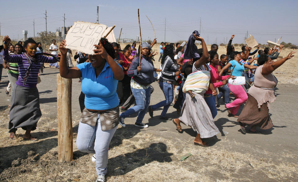 Women protest against the police near the scene of the shooting of miners Thursday at the Lonmin mine near Rustenburg, South Africa, Friday, Aug. 17, 2012. Frantic wives searched for missing loved ones, President Jacob Zuma rushed home from a regional summit and some miners vowed a fight to the death Friday as police finally announced the toll from the previous day’s shooting by officers of striking miners: 34 dead and 78 wounded. Placard reads: 'Come Zuma'. (AP Photo/Themba Hadebe)