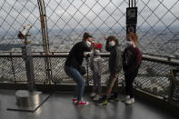 French visitors from south of France, Caroline, left, with her kids, Oxane, Rafaelle and Emma, from left to right, take a selfie from the third level during the opening up of the top floor of the Eiffel Tower, Wednesday, July 15, 2020 in Paris. The top floor of Paris' Eiffel Tower reopened today as the 19th century iron monument re-opened its first two floors on June 26 following its longest closure since World War II. (AP Photo/Francois Mori)