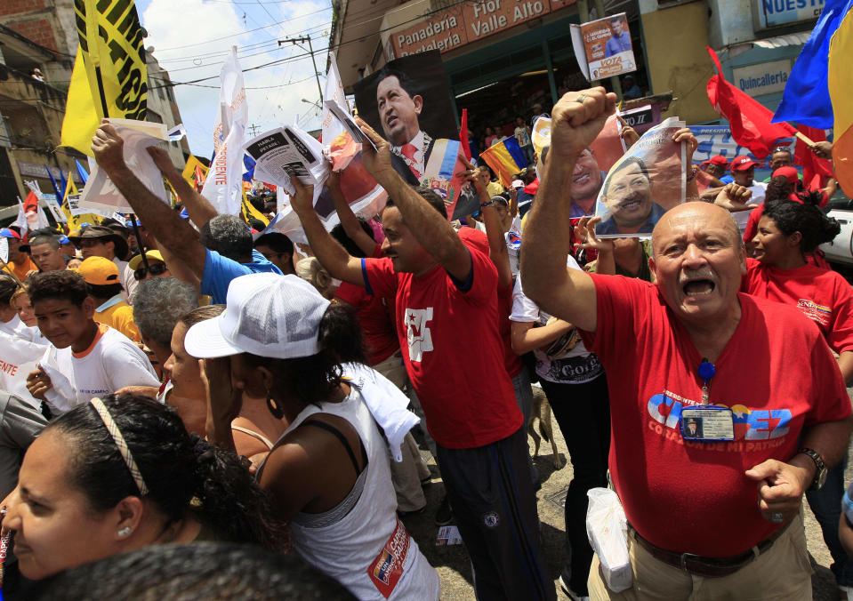 In this Sept. 16, 2012 photo, supporters of Venezuela's President Hugo Chavez wave photos of him as opposition presidential candidate Henrique Capriles campaigns in the Petare shantytown of Caracas, Venezuela. From single mothers to construction workers, a segment of Chavez supporters have been turning away from the president and instead considering new leadership. They've become key to the Oct. 7 presidential vote and Capriles' strategy. (AP Photo/Fernando Llano)