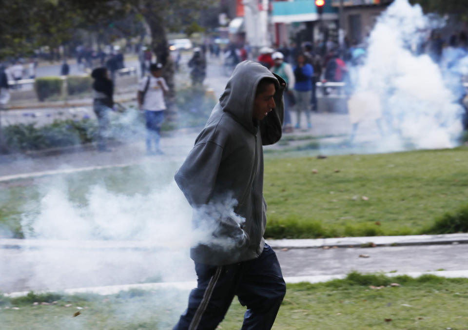 A protester run with a smoking tear gas canister to launch back at police, in Quito, Ecuador, Friday, Oct. 4, 2019, during a nationwide transport strike that shut down taxi, bus and other services in response to a sudden rise in fuel prices. Ecuador's President Lenín Moreno, who earlier declared a state of emergency over the strike, vowed Friday that he wouldn't back down on the decision to end costly fuel subsidies, which doubled the price of diesel overnight and sharply raised gasoline prices. (AP Photo/Dolores Ochoa)