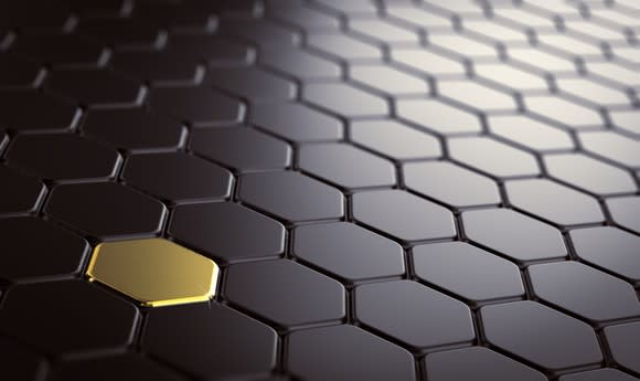 A surface comprising hexagons that are all black, except for one colored gold.