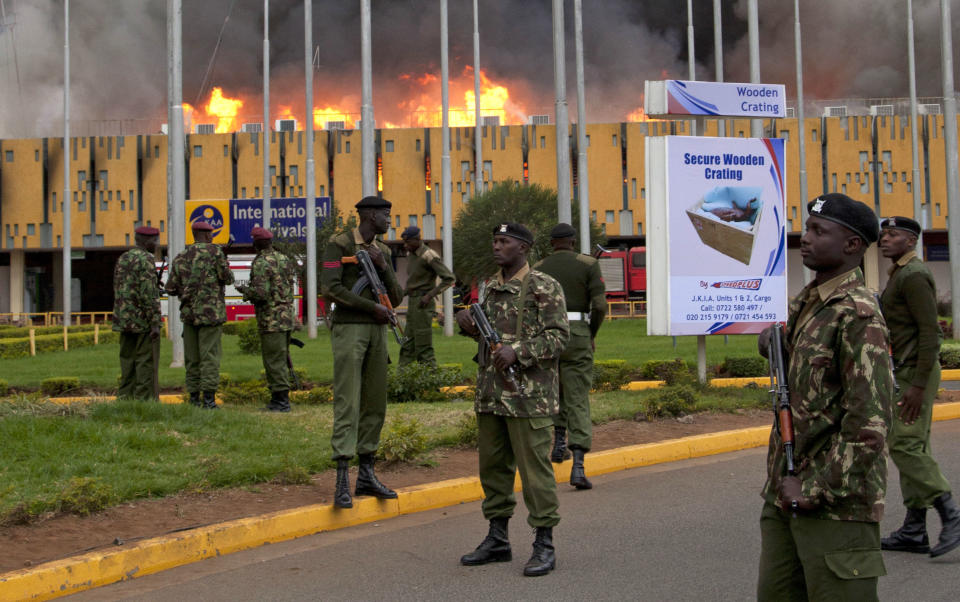 Armed policemen cordon off the area as fire rages at the international arrivals unit of Jomo Kenyatta International Airport, Nairobi, Kenya, Wednesday, Aug. 7, 2013. A massive fire engulfed the arrivals hall at Kenya's main international airport early Wednesday, forcing East Africa's largest airport to close and the rerouting of all inbound flights. Dark black smoke that billowed skyward was visible across much of Nairobi as emergency teams battled the blaze. (AP Photo/Sayyid Azim)